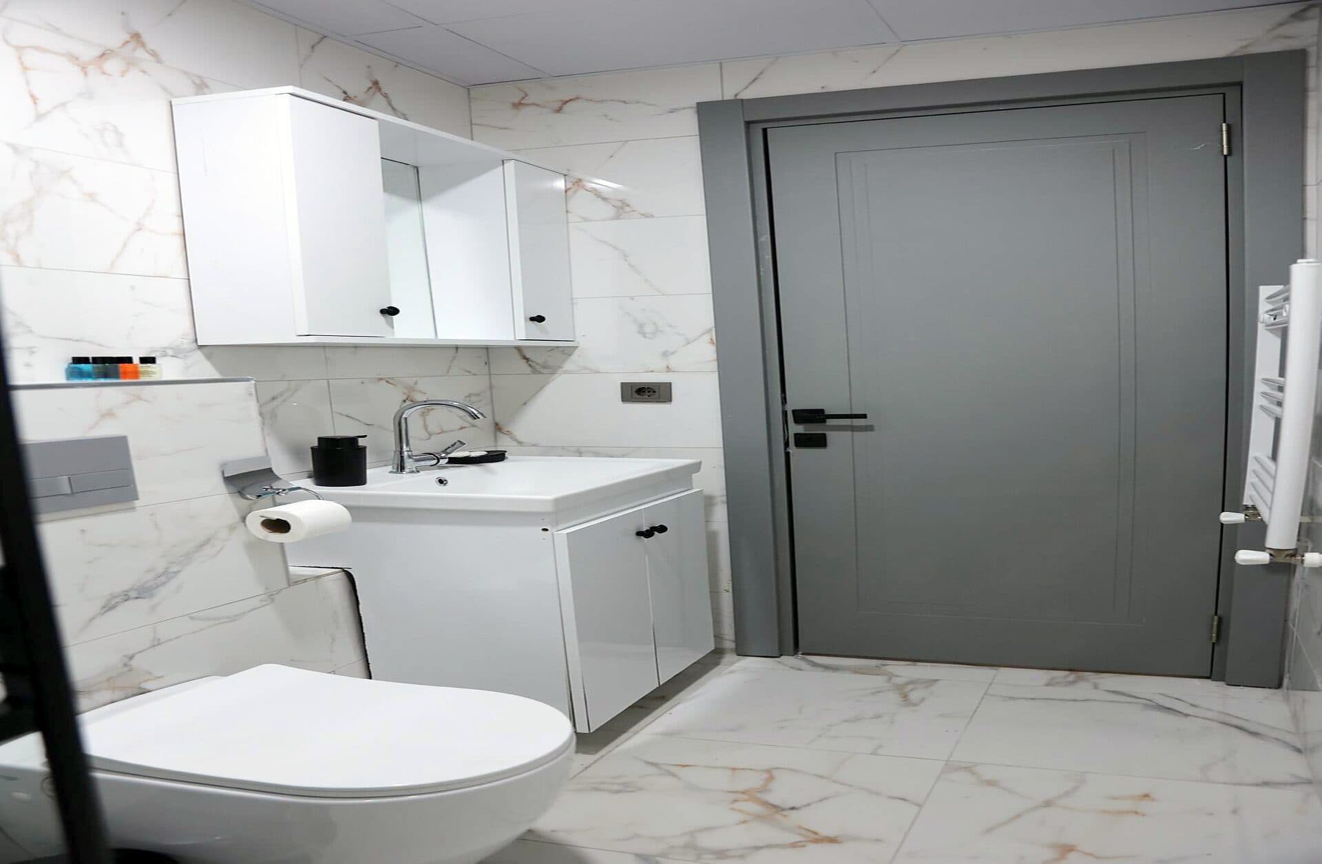 Orman manzaralı suit: ahşap dolaplı mutfak köşesi ve gri koltuklu oturma alanı — 5. fotoğraf