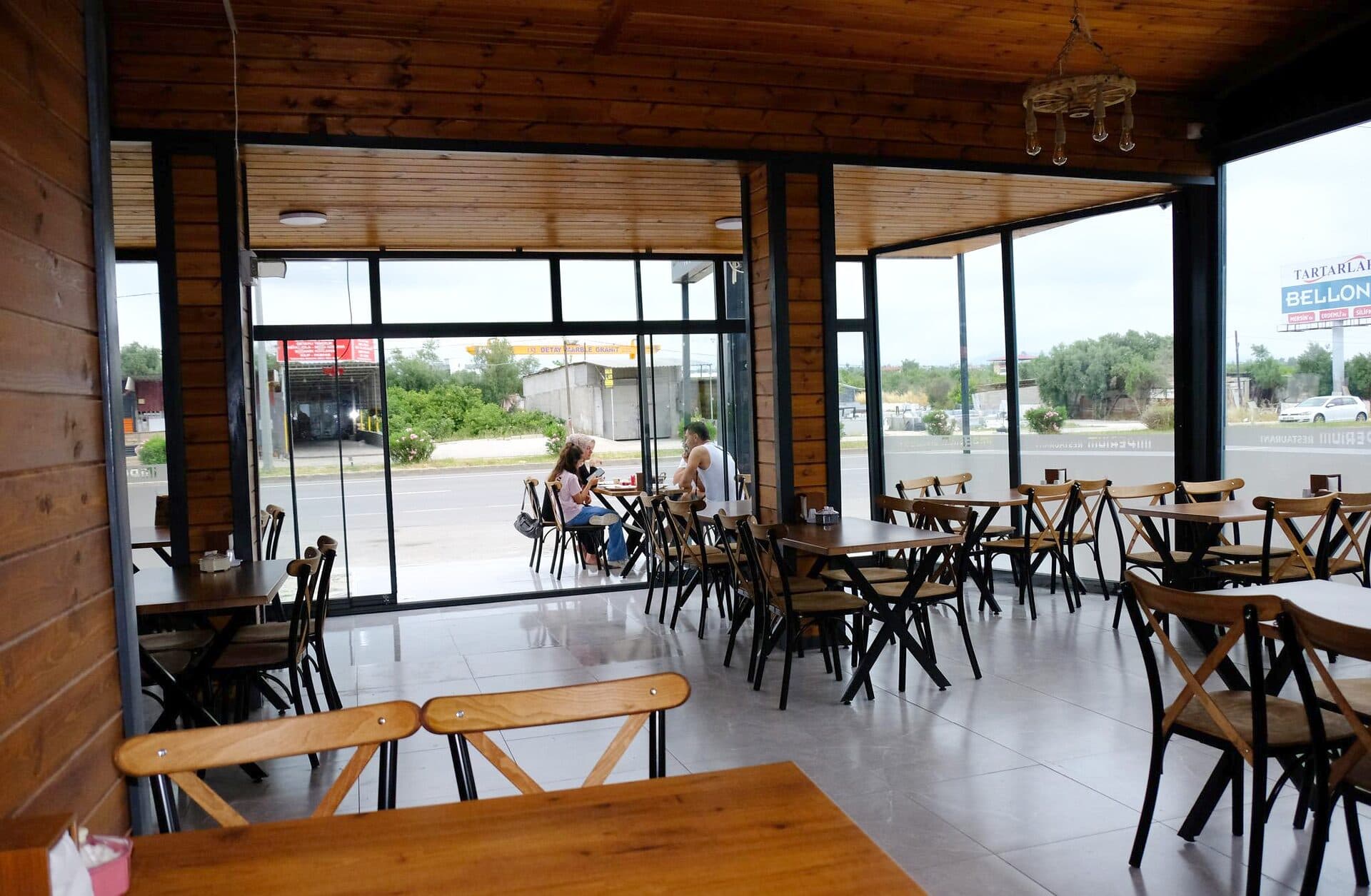 Restoranın cam cepheli bölümü ve zeytin ağaçlı dış manzara
